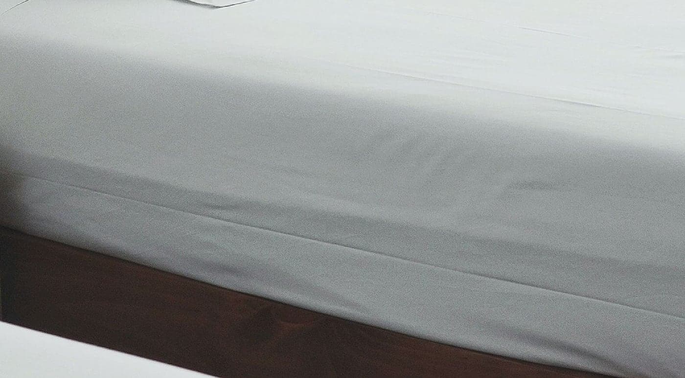 Fitted white sheet on a hotel mattress