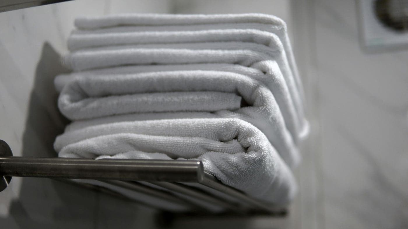 Folded white hotel bath towels on a rack